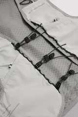 Chaleco deportivo técnico y ligero de color gris, diseñado con tejido de malla transpirable, múltiples bolsillos frontales elásticos, cierres de cordón ajustable y detalles reflectantes, ideal para running y actividades al aire libre.