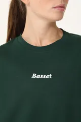 Remera verde con cuello redondo y manga corta. Estampado frontal con la palabra "Basset" en color blanco.