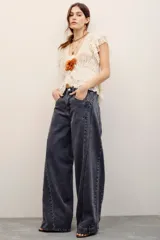 Pantalón jean de corte wide leg y tiro medio en color negro con efecto acid wash. Presenta costuras decorativas curvadas en la parte delantera y bolsillos laterales clásicos.