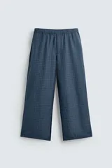 Pantalón de corte ancho (baggy fit) color azul marino con estampado de cuadros pequeños en tonos azul claro y marrón. Presenta cintura elástica ajustable con cordón interior y bolsillos frontales.