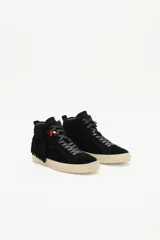 Zapatilla de caña media confeccionada en cuero vacuno descarne color negro, con detalle de flecos laterales y dije de corazón rojo en los cordones. Presenta suela de goma en tono crema.