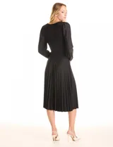 Vestido midi negro de satén, marca Sharagano. Presenta escote en V con aplique de guipur y lazo fino central. Mangas largas fluidas con puños fruncidos y hombros con leves frunces. La cintura tiene un lazo de ajuste que da paso a una falda de tablas plisadas.