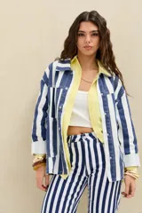 Campera de denim con diseño de rayas verticales en azul y blanco, de corte oversize, con cuello clásico, cierre frontal con botones metálicos y bolsillos appliqués en el frente.