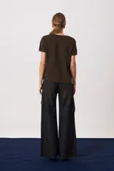 Pantalón cargo de tiro medio con pierna amplia y corte recto. Presenta bolsillos laterales tipo cargo con solapas y botones, además de recortes estructurales en la parte inferior de las piernas. Confeccionado en denim de algodón.