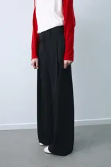 Pantalón de tiro medio color beige, de corte ancho y recto, con pinzas frontales y trabillas en la cintura.