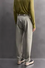 Pantalón de hombre color marrón oscuro, corte regular fit, confeccionado en tejido técnico compacto elástico. Presenta cintura ajustable con cinturón negro a contraste, bolsillos frontales, bolsillo trasero con cierre y bolsillo cargo con cierre en la pernera.