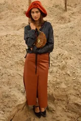 Falda larga de cuero genuino en color tostado, con diseño de tiro bajo y silueta recta. Presenta tajos laterales y un tajo central delantero, además de bolsillos funcionales delanteros y traseros.