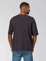 Remera de manga corta color gris oscuro con efecto lavado, cuello redondo y logo bordado en el pecho. Cuenta con un parche tejido en la manga.