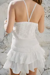 Vestido corto de viscosa y algodón, con escote en pico y tirantes finos cruzados en la espalda. Presenta un diseño con pliegues, aplicaciones de lazadas a contraste y falda con volantes en el bajo.