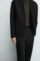 Pantalón de corte recto y ajuste relajado, confeccionado en una mezcla de algodón y lino. Presenta cintura elástica, bolsillos delanteros, bolsillo trasero de plastrón y cierre frontal con cremallera y botón.