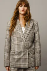 Blazer cruzado de sarga de algodón con estampado a cuadros en tonos beige, azul y marrón. Presenta solapas de pico, botones forrados, hombreras, un bolsillo superior insertado y dos bolsillos ribeteados con solapa. Las mangas tienen botones de cascada en los puños y cuenta con una abertura doble en la parte trasera.