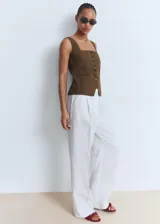 Chaleco de corte recto y diseño sin mangas, confeccionado en algodón. Presenta cuello escotado, cierre frontal con botones y dos bolsillos de ribete en la parte delantera.