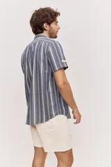 Camisa de manga corta color azul con diseño a rayas verticales, cuello clásico y cierre frontal de botones.