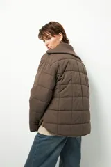 Campera acolchada de color marrón, con diseño capitoneado, cierre frontal completo y cuello alto de tejido acanalado.