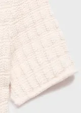 Jersey de punto de manga corta con diseño entallado, cuello redondo y detalle de volante en el bajo. Presenta una textura sutil en el tejido.