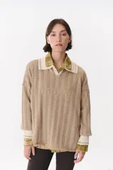 Remera tejida de punto con diseño de rayas verticales y textura calada, en color beige. Presenta un corte oversize con hombros caídos, cuello en V y puños en tejido acanalado en contraste.
