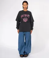 Camiseta de manga larga gris oscuro con efecto lavado, cuello redondo y mangas superpuestas (doble manga). Estampado frontal con texto en rosa que dice "GIRLS'N ROSES" y una rosa estilizada. Incluye pines decorativos en el cuello.