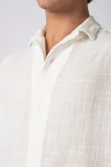 Camisa de manga corta confeccionada en una mezcla de lino y viscosa, con cuello plano y cierre frontal de botones. Presenta un diseño de calce regular con textura natural y acabado ligero.
