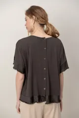 Remera negra de algodón con cuello redondo, mangas cortas y zócalo de satén desflecado en el ruedo y las mangas.