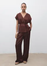 Pantalón de tiro medio en tejido satinado con efecto arrugado y diseño recto. Cuenta con bolsillos laterales, pinzas delanteras y cierre oculto con botón, gancho y cremallera.