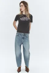 Camiseta de algodón con efecto lavado, cuello redondo y manga corta. Presenta un estampado frontal con texto en color claro.