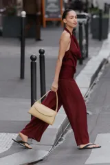 Mono largo de punto color bordó, con escote halter drapeado, hombros descubiertos y detalle de fajín fruncido en la cintura.