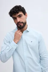 Camisa de manga larga fit semi slim color celeste, con cierre frontal de botones y cuello camisero clásico.