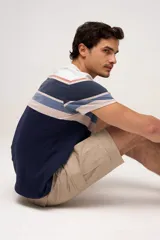 Bermuda cargo color azul marino, de gabardina con bolsillos laterales con solapa en las piernas y presillas para cinturón. Incluye cinturón de lona trenzada oscura con detalles en cuero sintético y hebilla metálica.