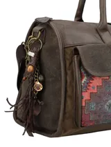 Cartera de mano marrón de estilo bohemio con detalles en tela étnica tipo tapicería bajo los bolsillos frontales con solapa. Cuenta con doble asa fija, correa ajustable y desmontable, cierre superior y llavero colgante con borla y cuentas decorativas.