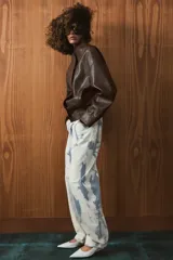 Jeans de tiro medio con corte barrel, confeccionados en algodón con estampado tipo tie-dye en tonos azul y blanco. Presentan diseño de cinco bolsillos, trabillas en la cintura y cierre frontal con cremallera y botón.