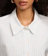 Camisa cropped de sarga con patrón de rayas celestes y blancas, cuello camisero, mangas cortas y cierre frontal con botones.