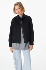 Chaqueta corta de paño color gris, con cuello alto, cierre frontal con cremallera y bolsillos delanteros con solapa.