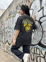 Remera negra con efecto lavado y estampado de tres caras sonrientes amarillas y texto "Nothing Serious". Corte oversize.