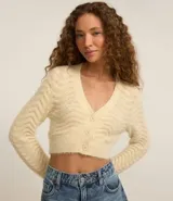 Cardigan cropped color crema con escote en V, manga larga y punto ondulado.