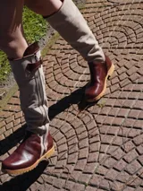 Botas altas de cuero marrón combinadas con gamuza blanca con estampado de vaca, forradas en cuero y con cierre de bronce.