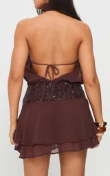 Vestido corto marrón con escote halter fruncido, cintura alta con aplique de lentejuelas y falda con volados en capas.
