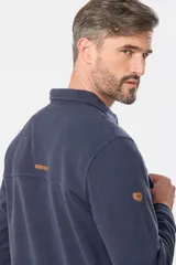 Camisa azul marino de poliéster con textura polar, corte recto, cuello camisero, cierre frontal con botones a presión, dos bolsillos de parche con solapa abotonada en el pecho y puños abotonados.