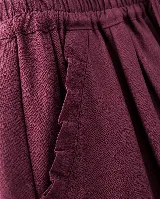 Pantalón de lino color bordó, de silueta relajada y amplia, con cintura elastizada, lazo de ajuste y detalle de pequeños pliegues y ruedo desflecado.