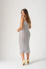 Vestido tejido al crochet color gris plata, de corte midi, con breteles finos y flecos en el ruedo.