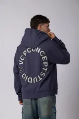 Buzo canguro oversize de frisa de algodón premium en color azul grisáceo. Presenta un diseño con recortes frontales, bolsillo tipo canguro y un pequeño logo circular estampado en el pecho. Cuenta con puños y ruedo acanalados.