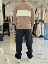 Hoodie de corte clásico con medio cierre y cuello alto, en color marrón con una franja horizontal blanca en el pecho que incluye el logo estampado en negro. Presenta además un pequeño bordado en el hombro izquierdo y puños y cintura elastizados de rib.