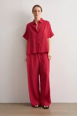 Camisa de manga corta color rojo, de corte holgado, con cuello camisero clásico y cierre frontal abotonado.
