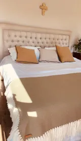 Manta rectangular color beige de lana merino con flecos blancos en los bordes.