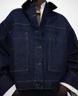 Chaqueta boxy denim de algodón orgánico y reciclado, color azul, con cuello italiano, mangas largas amplias, botonadura frontal y bolsillos delanteros con doble entrada.