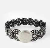 Cinturón negro con apliques circulares plateados y hebilla circular plateada con diseño labrado.