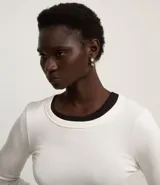 Blusa blanca de rib con cuello redondo y mangas largas.