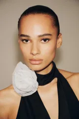 Body negro de cuello halter con escote drapeado pronunciado, detalle de flor blanca en relieve y espalda descubierta.