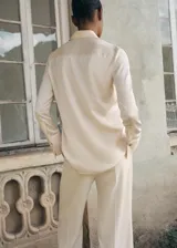 Camisa de corte clásico con acabado satinado, cuello camisero, cierre frontal con botones y manga larga con puños abotonados.