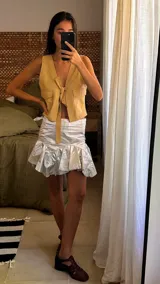 Minifalda de cuero color marrón oscuro, con fajón en la cintura y volados en el ruedo.