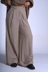 Pantalón negro de corte sastrero con tablas frontales y cintura con lazo. Diseño de pierna ancha y tiro alto.